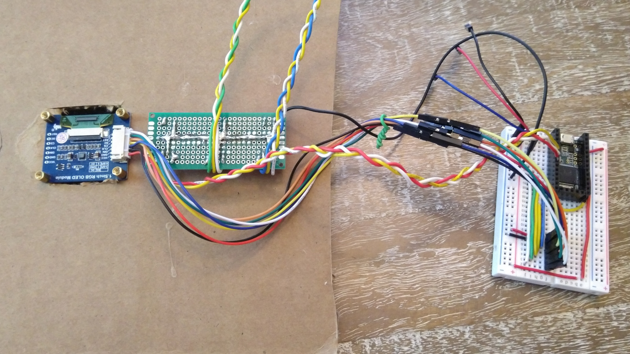 Electronics mounted to cardboard. One set of wires goes to a microcontroller board. Two more go off-screen.